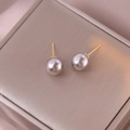 Elegante silbergraue Perlenohrstecker mit goldenen Stiften auf champagner Seidenhintergrund - Mittel / Grau