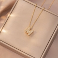 Elegante collana dorata con lettera M e zirconi luccicanti su sfondo di raso champagne - Letter M (X4208)