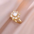 Makro-Detail eines goldenen Blumenrings mit Zirkonia auf champagnerfarbenem Satin - Gold Rotierender Zirkonia Ring