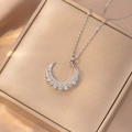 Detailed close-up of a silver moon pendant with zircon stones on a champagne silk background - Pave Zirconia Crescent Moon Style (X4190) / Silver