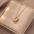 Nahaufnahme der goldenen Kette mit U-Buchstaben-Anhänger und Zirkonia auf Geschenkbox - Buchstabe U