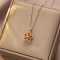 Detailansicht eines goldenen rotierenden Blumenanhängers mit roten Zirkonsteinen - Orange Weiß Bauhinia Rotierender Stil (X1310)