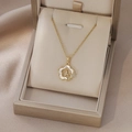 Gros plan d'un pendentif fleur dorée avec nacre et zircons dans un coffret cadeau - Style Fleur Nacre Français Or (X4367)