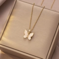 Elegante gouden vlinderhanger ketting met kristallen op een beige sieradendoosje - Gouden Marmeren Textuur Vlinder Stijl (X4314)