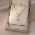 Dettaglio di una collana a coda di balena blu con zirconi in una scatola regalo - Stile Coda di Pesce Blu Oro (X4392)