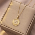 Nahaufnahme des goldenen Münzanhängers mit Sonnenstrahl-Textur und Kristallbuchstabe B - Gold - Buchstabe B