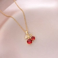 Close-up of cherry pendant with red gems and gold leaves on pink satin fabric - Red Gemstone Cherry Style (X4433) / Gold