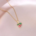 Minimalist cherry pendant necklace with pink and green gems on a soft pink satin fabric - Pink and Green Zirconia Cherry (X4434) / Gold