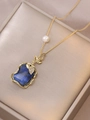 Detailansicht einer goldenen Kette mit blauem Stein und Perle auf einer Satin-Schmuckschatulle - Dunkelblauer Naturstein Anhänger (X3672)