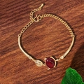 Details des Fuchs-Armbands in Gold mit rotem Edelstein und Blatt auf dunklem Holzgrund - Gold Fuchskopf (TS0309)