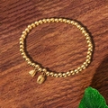 Vergoldetes Perlenarmband im Vintage-Stil mit Lotusanhängern auf Holzhintergrund - Goldschmuck Lotus Anhänger Perlen Stil / Gold Lotus Perlen (TS0248)