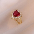 Elegante anello dorato con gemma a cuore rossa e aureola di cristalli su sfondo di seta - Cuore Rosso Halo Diamante Stile Elegante (J0201)