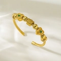 Détail du bracelet doré torsadé avec breloques en cœur et pierres de zircon vert brillant - Style Cœur Zirconium Vert et Couronne (TT0845)