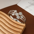 Silver flower bangle with seven daisy charms and sparkling crystals on triple bands - Steel