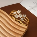 Detail of gold open bangle with white daisy floral design and sparkling rhinestones - Gold