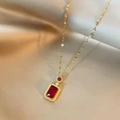 Macro shot of an 18K gold plated necklace with a red rectangular gemstone on silk - Necklace / Red Rhinestone Gold Plated