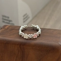 Nahaufnahme eines Vintage-Blumenrings mit rosa Emaille-Blüten auf dunklem Holzgrund - Rosa und Weißer Blütencluster Stil (JZ3704A)
