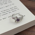 Nahaufnahme eines sternförmigen Rings mit lila Zirkonia auf einer Vintage-Buchseite - Einstellbar Offen / Sternform (JZ0360A)