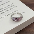 Makro-Detail von silbernem verstellbarem Ring mit lila Zirkonia-Steinen auf altem Buch - Einstellbar Offen