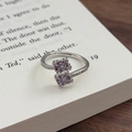 Nahaufnahme eines eleganten Blumenrings mit lila und rosa Zirkonia auf einer Buchseite - Einstellbar Offen / Quadratischer Cluster-Stil (JZ4370A)