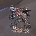 Exquisite silver bow ring featuring a pink rectangular zircon and hollow carved details - Right Ear