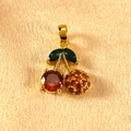 Detailed close-up of cherry pendant with sparkling green leaves and red stones on satin - Gold Green Leaf Red Rhinestone Cherry Pendant