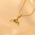 Makroaufnahme von goldenem Meerjungfrauenschwanz-Anhänger und Kette auf Seide - Meerjungfrauenschwanz-Stil / Gold Gelb