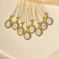 Nahaufnahme goldener ovaler Buchstabenanhänger mit weißem Emaille auf Edelstahlkette - Halsketten-Set / Buchstabe A