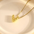 Detail einer goldenen V-Halskette mit strukturierter Oberfläche auf einer weißen Platte - Halskette V / 40+5cm