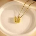 Detailansicht des goldenen U-Anhängers mit Punkt-Textur und Box-Kette auf weißer Keramik - Halskette U / 40+5cm