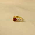 Detail van vergulde open ring met een dieprode edelsteen en witte zirkonsteen - Rode Steen + Witte Steen