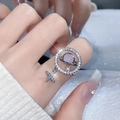 Makroaufnahme eines silbernen Saturn-Rings mit rosa Stein und Kreuzanhänger am Finger - Einstellbar Offen / Zirkon Saturn Anhänger Stil (JZ3728)