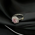 Detalle macro de anillo plateado ajustable con gema rosa sobre elegante seda negra - Estilo Halo Redondo Rosa (JZ4611)