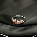 Primer plano del anillo ajustable de plata con piedra naranja sobre seda negra - Anillo Abierto Engaste de Garras Naranja (JZ4625)