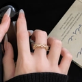 Dettaglio dell'anello dorato ondulato con gemma rosa e pavé di zirconi bianchi lucidi - Gemma Rosa Onda Fascia Dorata (JZ4670)