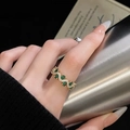 Dettaglio anello ondulato dorato con gemme verde smeraldo e pavé di zirconi brillanti - Gemma Verde Onda Fascia Dorata (JZ4666)