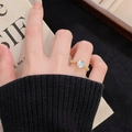 Macro detail of gold ring with iridescent gemstone worn on finger in luxury setting - Adjustable Open / Round Moonstone Style (JZ4501)