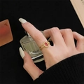 Detail van vintage kanten ring met rode zirkoon op model die parfumflesje vasthoudt - Roze Edelsteen Holle Golf Stijl (JZ5349)