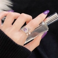 Detalle de anillo con gema púrpura en plata S925 y dije colgante en la mano del modelo - Estilo Colgante de Borla Calado Llama Púrpura (JZ5604)