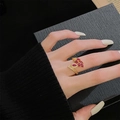 Détail d'une bague dorée ajustable ornée de pétales en zircon rouge et petits diamants - Style Papillon Floral Zircon Rouge (JZ4545)
