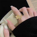 Gros plan d'une bague papillon dorée vintage avec perles sur le doigt d'une femme - Style Perle Fleur Papillon (JZ5135)