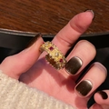 Close-up of vintage gold ring with red and white gemstones and hollow patterns - Hollow Pattern Red White Gem (JZ5715)