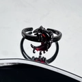 Detail of gothic moon ring with red stone and black alloy finish on reflective surface - Dripping Moon Gothic Style (JZ6030)