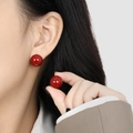 Boucles d'oreilles élégantes en acier doré avec perle rouge brillante sur modèle - Acier Rouge
