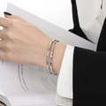 Bracelet géométrique argenté minimaliste au design facetté porté par un modèle élégant - 58mm / Argent