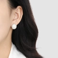 Boucle d'oreille rose blanche sculptée en titane doré portée par un mannequin - Blanc Acier