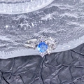 Makroaufnahme eines funkelnden Rings mit blauem Zirkon und Diamanten auf Glastablett - Runder Sternen-Stil (JZ5583)
