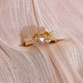 Détail macro d'une bague coeur dorée avec zircon rose et design couronne ailée ciselée - Ouvert Réglable / Style Cœur Couronne Ailes (JZ0783A)