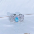 Dettaglio di un anello a fiocco in argento con gemma azzurra e pavé di zirconi bianchi - Aperto Regolabile / Stile Curva a Fiocco con Pietra Celeste Ovale (JZ0408A)