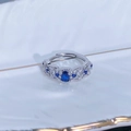 Vista macro di un anello regolabile in argento con pietra blu e zirconi incastonati a pavé - Aperto Regolabile / Stile Svuotato Vintage con Pietra Principale Blu Ovale (JZ4522)